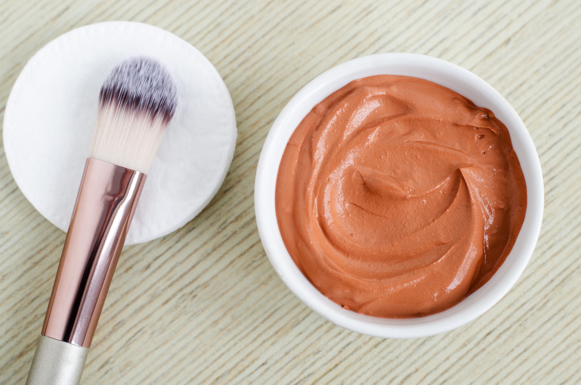 Small white bowl with red cosmetic clay mask. Homemade beauty treatment. Copy space.