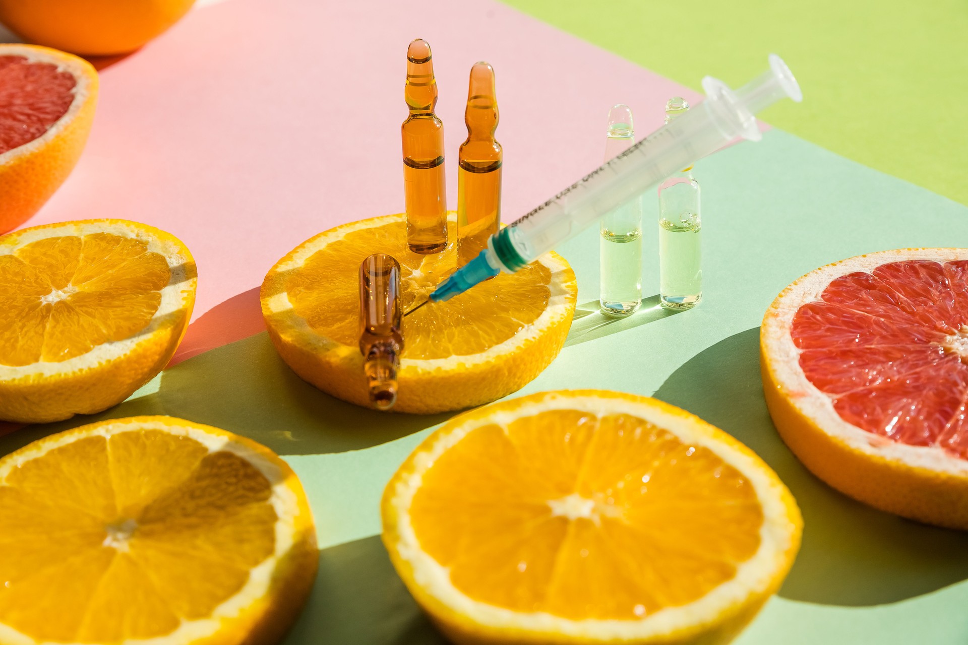 ampoules and Serum with Vitamin C. Organic cosmetics concept. Lemon, orange, grapefruits and ampoules on a light background. Injection of vitamin.Comineral supplement concept. Beauty products.