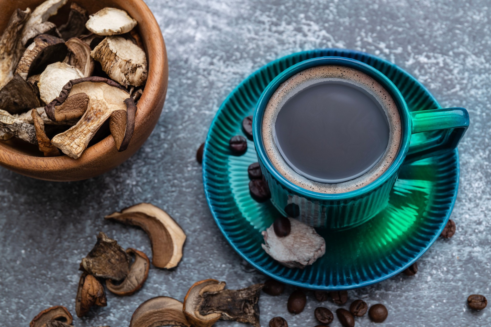 A cup of coffee with mushrooms and coffee beans on a dark background with copy space.